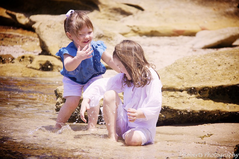 Sisters splashing each other at the beach - family portrait photography sydney